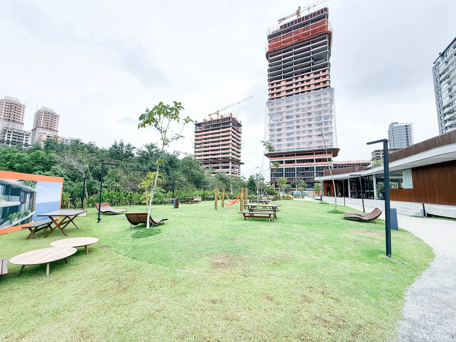Torres do Lagom Perequê em construção vistas do gramado, com mesas, redário e a mata ao lado